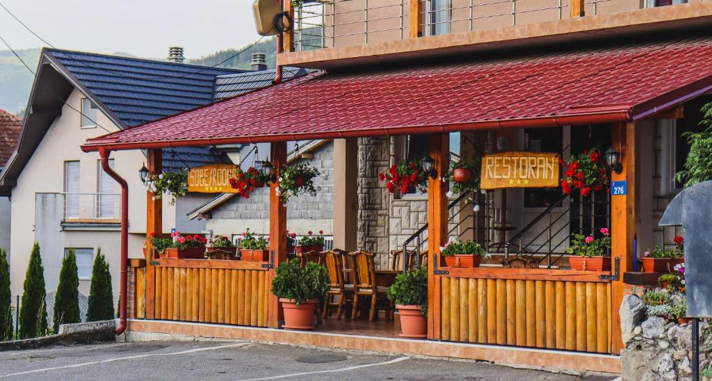 Drvena terasa restorana Manjež sa cvijećem i oznakama Restoran i Sobe / Rooms u Bijelom Polju
